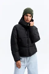 Campera puffer negra con cuello alto, cierre frontal y bolsillos laterales con cierre. Diseño acolchado de volumen medio.
