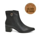Bota corta de cuero negro con taco cuadrado y punta fina. Presenta un detalle metálico dorado con logo en el lateral superior y cierre lateral.