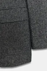 Blazer de corte sastrero confeccionado en tejido de lana con diseño de espiga. Presenta cuello con solapas, hombreras, cierre frontal con un botón y bolsillos delanteros con solapa.