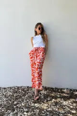 Pantalón amplio color naranja con estampado abstracto en blanco, cintura elastizada y bolsillos laterales.