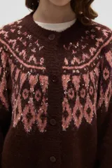 Cardigan de tejido jacquard con diseño geométrico en la parte superior, cuello redondo y cierre frontal con botones. Presenta un corte holgado y mangas largas con puños acanalados.