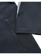 Campera deportiva Under Armour modelo Velocti Strm Hdd, color negro con capucha y cierre frontal. Cuenta con tecnología UA Storm impermeable, detalles reflectantes y diseño con paneles grises y franjas en las mangas.