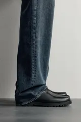 Zapato de cordones de estilo derby, color negro, con parte superior lisa, detalle de bordón en el empeine, horma redonda y suela track dentada.