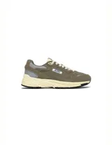 Championes urbanos Autry modelo Hyperway Low, color verde oliva con detalles en gris y crema. Confeccionados en una combinación de gamuza y malla técnica, presentan el logo de la marca en el lateral y una suela con tecnología Action Cush.