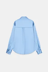 Camisa de cuello solapa y manga larga, confeccionada en tejido satinado con acabado brillante. Presenta cierre frontal con botones y bajo asimétrico.