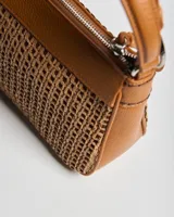 Bandolera color habano con cuerpo de tejido texturizado y detalles en símil cuero. Cuenta con asa corta superior y correa ajustable y desmontable.