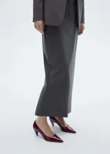 Falda larga de estilo sastre, color gris, con diseño tipo lápiz, tiro medio, bolsillos laterales y abertura posterior.