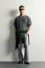 Jeans flare fit de denim de algodón en color gris con efecto lavado. Presentan diseño de cinco bolsillos, tiro medio y cierre frontal con cremallera y botón.