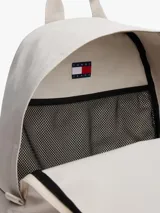 Mochila de diseño redondeado en color gris claro, confeccionada en poliéster texturizado. Cuenta con un compartimento principal con cierre, un bolsillo exterior con cremallera en la parte frontal y un bolsillo interior de malla abierto. Posee asa superior y correas ajustables y acolchadas. Lleva un parche tejido de Tommy Jeans en la parte delantera.