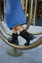 Bota tejana de cuero negro con bordado de cactus en hilo blanco.