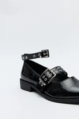 Zuecos de charol color borgoña con punta fina, correa al tobillo y doble tira sobre el empeine con hebillas metálicas plateadas.