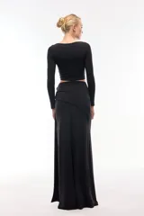 Falda larga negra con tajo lateral alto y detalle de argollas metálicas.