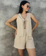 Chaleco tejido color beige con lurex, escote en V y lazos para atar en el frente.