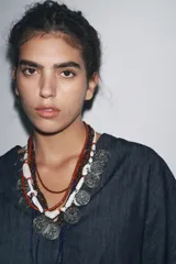 Camisa de tejido tipo denim azul oscuro, con escote pico, manga corta ancha y dos bolsillos de parche frontales. Cierre frontal con botones.