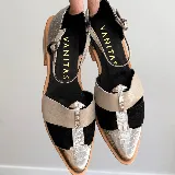 Zapato cerrado tipo sandalia de Vanitas, confeccionado en cuero vacuno. Presenta un diseño tricolor con paneles en negro, beige y detalles en cuero plateado con textura de reptil. Cuenta con punta fina, taco de madera de 4 cm y cierre con pulsera al tobillo.