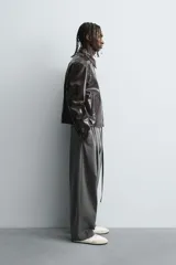Pantalón de corte balloon fit en color gris, confeccionado en tejido con viscosa. Presenta pliegues frontales, cintura con cinturón integrado a contraste, bolsillos laterales y bolsillos traseros de vivo.