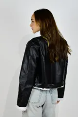 Campera de cuero sintético color negro con corderito blanco en cuello, puños y ruedo. Cuenta con cierre frontal, bolsillos laterales con cierre y tiras ajustables con hebilla en la cintura.