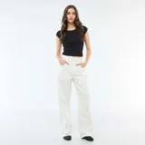 Pantalón de jean con corte globo, tiro alto y diseño de pierna ancha. Presenta cierre frontal con botón y bolsillos laterales.