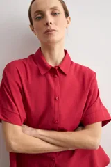 Camisa de manga corta color rojo, de corte holgado, con cuello camisero clásico y cierre frontal abotonado.