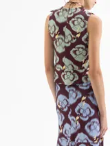 Top sin mangas de viscosa, con escote redondo y volado en el ruedo. Presenta un estampado full print con motivos florales y figuras humanas estilizadas en tonos borgoña, verde menta y amarillo.