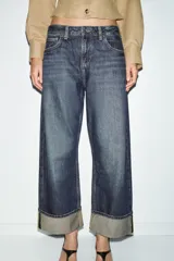 Jeans de tiro medio con corte relax fit y pernera holgada. Presenta diseño de cinco bolsillos, cierre frontal con cremallera y botón, y bajo con vuelta marcada.