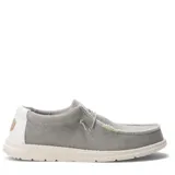 Zapatos tipo slip-on de tela color beige, con diseño de costuras expuestas, cordones elásticos decorativos y suela de goma blanca.