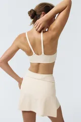 Top deportivo de soporte medio color beige claro con escote redondo y doble tirante en los hombros.