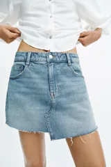 Falda pantalón de denim azul con diseño de cinco bolsillos, cierre frontal con cremallera y botón, y bajo deshilachado sin costuras.