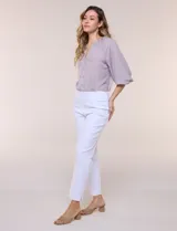 Pantalón ankle de tiro alto color blanco, confeccionado en tejido elástico con pretina ancha tipo pull-on, corte entallado y detalle de encaje calado en las aberturas laterales del ruedo.