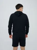 Campera deportiva Umbro modelo Terrace, color negro, con capucha y cierre frontal completo. Cuenta con bolsillos tipo canguro y detalles de la marca en las mangas.