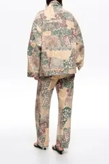 Chaqueta larga de corte oversize confeccionada en algodón con estampado patchwork en tonos beige, verde y marrón. Cuenta con cierre frontal con botones, cuello camisero, mangas largas, bolsillos con solapa en el pecho y bolsillos laterales.