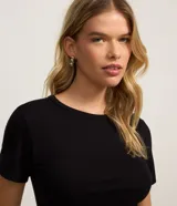 Blusa básica de manga corta y cuello redondo, confeccionada en viscosa texturizada de canalé con elastano y detalle de terminación ondulada en el bajo.