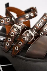 Sandalias de cuero color marrón con plataforma negra y hebillas metálicas.