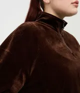 Campera deportiva de plush color marrón, con cuello alto, cierre frontal parcial y mangas largas con puños elásticos. Presenta una textura acanalada y un corte holgado.