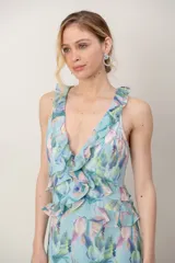 Vestido largo de gasa verde agua con estampado floral en tonos pastel, escote en V profundo, espalda cruzada con tirantes regulables y detalles de volados en los tirantes y en el ruedo.