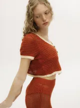 Top tejido calado color ladrillo, con cuello en V, mangas cortas y botones carey en el frente.