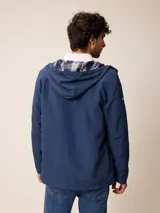 Campera de nylon con cierre frontal, capucha ajustable con cordones y forro interior a cuadros. Presenta bolsillos laterales y logo bordado en el pecho.