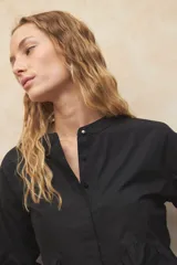 Camisa blanca de manga larga y cuello mao, estilo victoriano. Cuenta con un botón plateado a la vista.