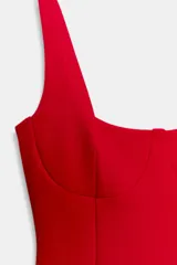 Vestido corto de tejido de punto elástico, con escote redondo, tirantes anchos y costuras marcadas que definen el busto. Presenta un diseño ajustado con cierre lateral oculto.