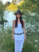 Vestido largo blanco de corte recto con escote strapless y falda con volados en el ruedo que aportan transparencia y movimiento.