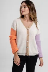 Cárdigan de punto color crema con mangas largas y terminaciones en color naranja y lila. Posee cuello en V y cierre frontal con botones color madera.