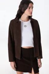 Chaqueta marrón de cuero vacuno descarne, con cuello camisero, corte entallado con pinzas y mangas sastre. No tiene botones.
