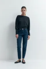Jean slim de tiro alto color azul oscuro, con corte ajustado desde la cadera hasta el tobillo y largo hasta el tobillo.