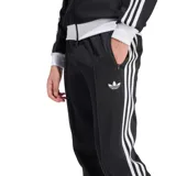 Pantalón deportivo Adidas modelo Beckenbauer, color negro con las icónicas tres rayas blancas laterales y logo del trébol bordado. Confeccionado en tejido de piqué, presenta corte entallado, bolsillos laterales con cierre y cintura con cordón de ajuste.