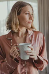 Pijama de satén elastizado color celeste, compuesto por una camisa de manga larga con cuello solapa, botones frontales y bolsillo en el pecho, y un pantalón recto con cintura elástica y lazo ajustable.