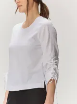 Remera de manga larga color blanco con cuello redondo y detalles fruncidos con lazos en las mangas.