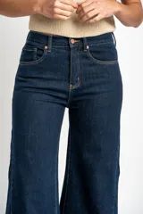 Jean de corte wide leg y tiro medio, confeccionado en denim de algodón. Presenta costuras verticales decorativas a lo largo de las piernas y cierre frontal con botón y cremallera.