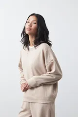Buzo de manga larga color marrón chocolate, con silueta relajada, hombros caídos y diseño minimalista. Confeccionado en tejido suave con caída fluida.