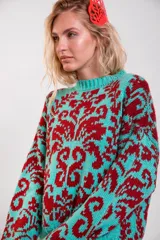 Sweater de punto con diseño estampado en color turquesa y bordó, de corte holgado, con cuello redondo y mangas largas.