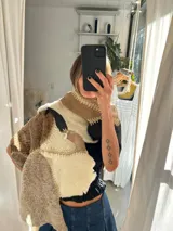 Ruana artesanal confeccionada con piezas de napalán unidas mediante costuras de crochet. Presenta un diseño de patchwork en tonos tierra, marrones y crema, con capucha integrada.
